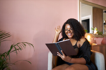 attractive overweight afro woman interested in book, enjoy reading book at home in weekends, sits...