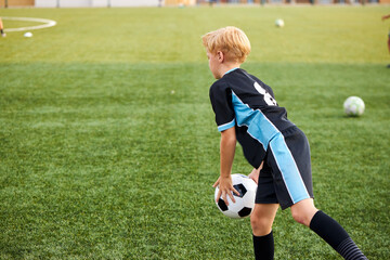 young kid boy training with soccer ball alone in stadium, practice various tricks, before game