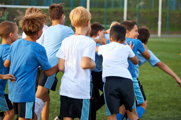 Obraz premium rear view on happy cheerful team of young football players celebrating their win in game, they run and have fun