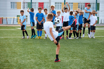 Obraz premium young caucasian players on soccer training. kids practicing european football on the grass field in stadium. children lead healthy lifestyle