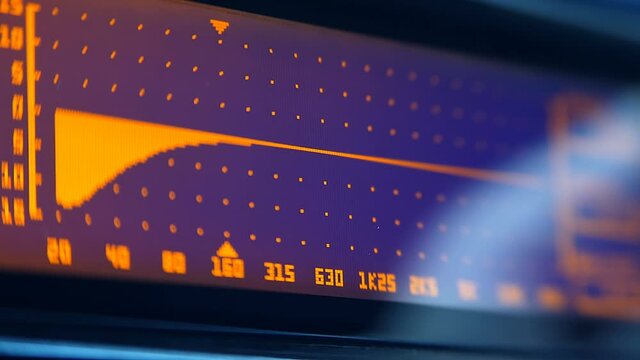 The professional concert parametric equalizer has a yellow spectrum analyzer on the display that analyzes the frequency range of music or any sound and can change it. The hand turns the knob