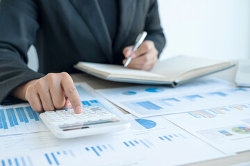 The hand of an accountant woman is analyzing and calculating the financial graph showing the results in the office