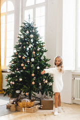 Girl with long hair in a white sweater around the Christmas tree, new year and Christmas tree, gifts