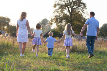 Happy family: mother, father, children, son and daughters in nature at sunset. Parents and children are walking together. The large family.