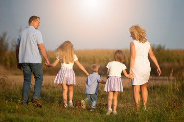 Happy family: mother, father, children, son and daughters in nature at sunset. Parents and children are walking together. The large family.