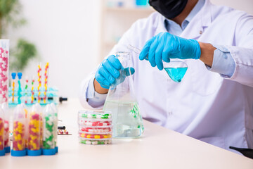 Young male chemist in drug synthesis concept