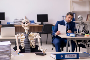 Young male employee with skeletons in the office