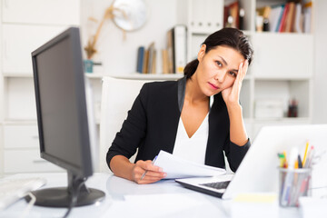 Worried young kazhahstani woman manager working with documents at the office table