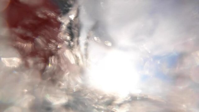 View from underwater of a boat advancing on the surface of the sea. Bubbles are created by the motion and the deep blue ocean can be seen. Swimming next to boat.