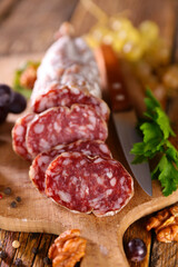 sausage on wooden board with walnut and grapes