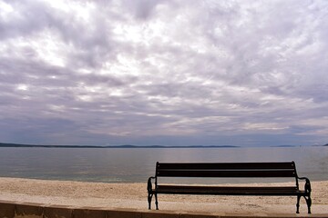 Naklejka na ściany i meble Wooden bench at the beach/ Beautiful sea landscape on winter cloudy day 