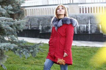  blond business woman in red fox fir dawn jacket with hood closeup photo on city park background