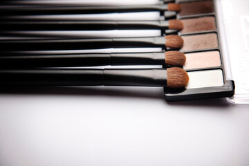makeup brushes and eyeshadow set on white background top view
