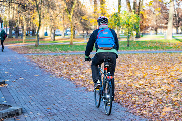 Naklejka premium Rider cycling on the road bike in the city in autumn, sustainable transport concept