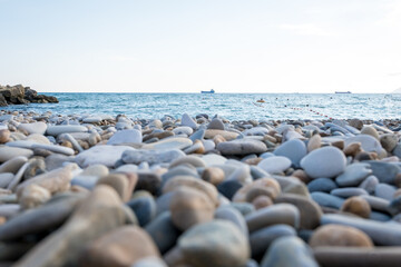 Fototapeta na wymiar pebble beach. Sea and ship in the background. Pebble close up.