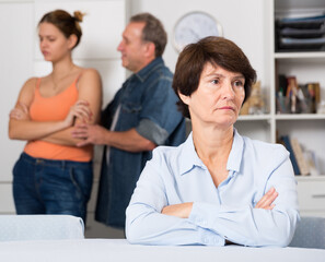 Adult woman is upseting and her husband with daughter are sympathying with her at home.