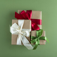 Beautiful packaging of presents with multicolor satin ribbons, craft paper on the green background.