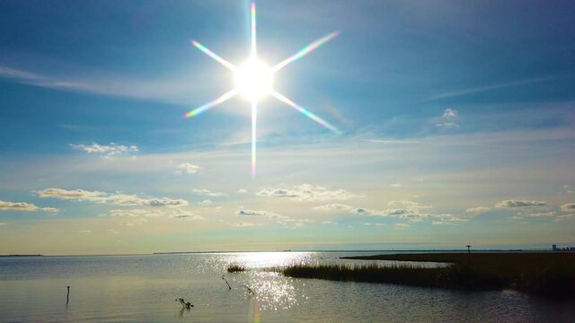4K MOTIONLAPSE pan left to right from sun and reflection on waterway to Atlantic City skyline in distance with partly cloudy sky