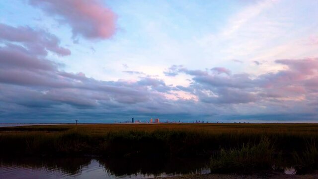 HD TIMELAPSE Atlantic City Skyline northern view from the water along Galloway Township near Absecon, NJ New Jersey with stunning cloudy sky turning pink, purple and blue, also available in 4K