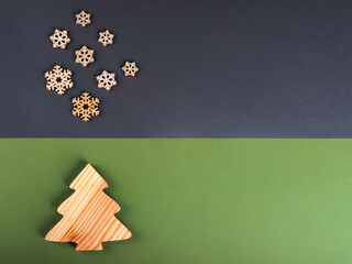The zero waste new year concept as a handmade wooden conifer tree and falling wooden snowflakes with copyspace on the grey and green background.