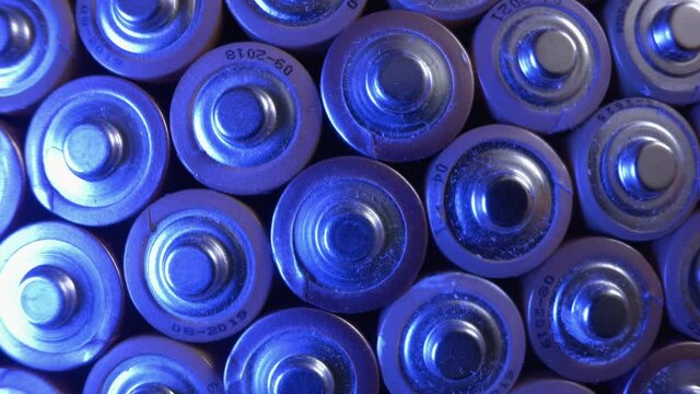 Many old alkaline batteries illuminated by a blue lamp