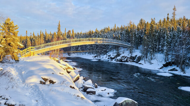snow covered river flowing under a bridge near Cameron river falls NT