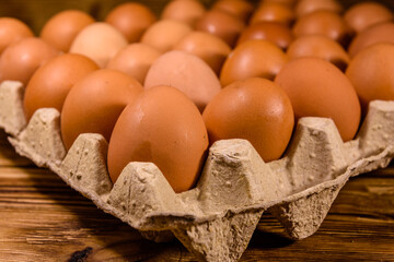 Pile of the hen eggs in paper tray on wooden table