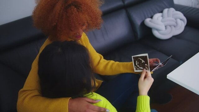 Lesbians waiting for baby Embracing and looking at ultrasound picture. . High quality 4k footage