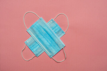 two medical masks in blue on a pink background