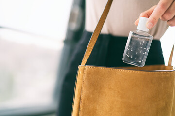 COVID-19 hand sanitizer woman using small sanitiser bottle in bag when going out walking to work in...
