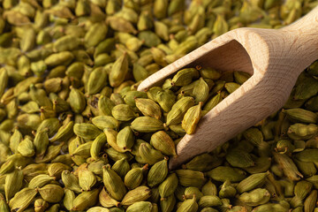 Closeup cardamom seeds with wooden scoop