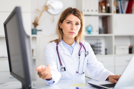 Female doctor making welcome gesture, politely inviting patient in medical office