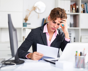 thoughtful adult male manager working with docs