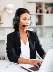Young asian woman call centre operator with headphones during working in modern office