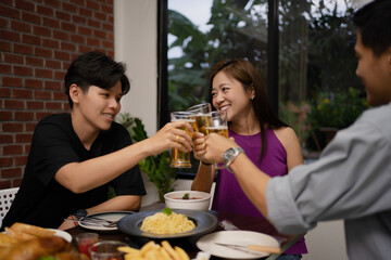 Young asian group are drinking beer and the clink glasses in a restaurant.