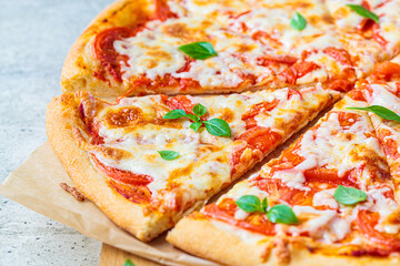 Classic pizza Margherita with mozzarella, tomato and basil on wooden board. Italian food concept.
