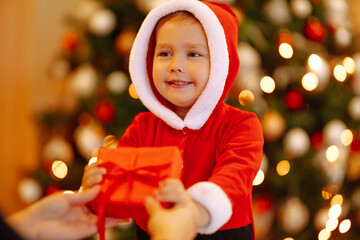 Christmas gift in the hands of a child. Cute little boy  receiving christmas present from parent. Winter holiday, New Year.