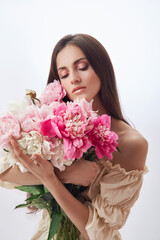 Beautiful woman with lots of pink flowers in her hands. Sexy woman with long hair