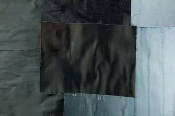 Black and grey torn crumpled magazine paper with dirty glue marks and stains. Abstract background...