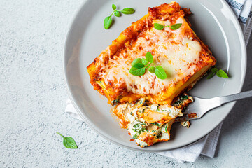 Piece of cannelloni with ricotta and spinach on a gray plate, top view. Italian food concept.