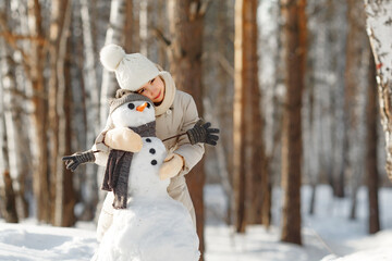 happy child girl plaing with a snowman on a snowy winter walk