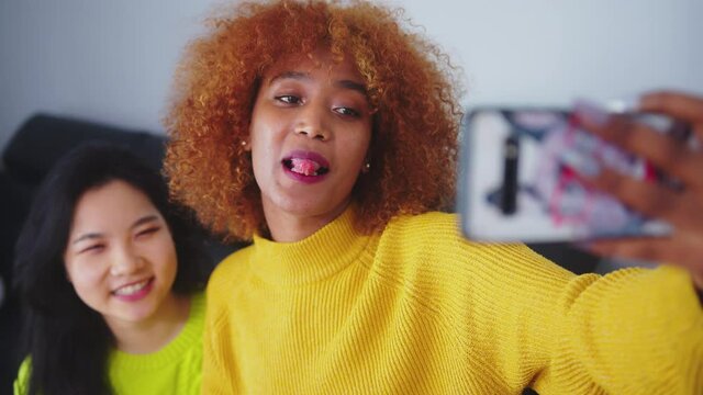 Best friends Asian and african american black woman taking selfie using smartphone. Funny faces. High quality 4k footage