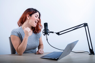 An emotional woman is broadcasting online on a laptop. Female radio presenter at the workplace