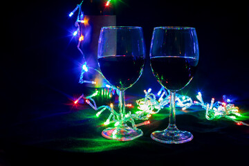 two wine glasses in a shining garland with a toy christmas  tree