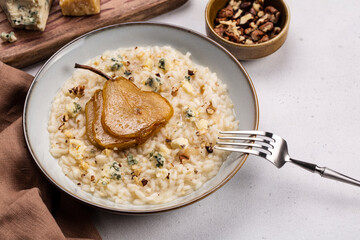 Pear and gorgonzola risotto with walnuts on white table. Ingredients on background. Copy space.