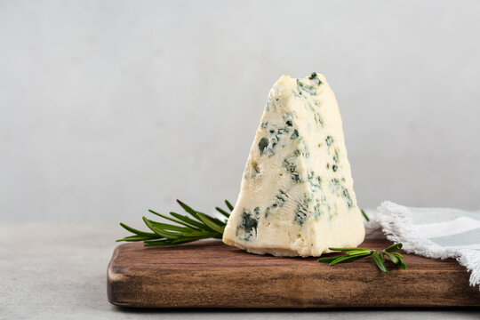 Gorgonzola - italian veined cheese on light grey background, with  rosemary. Copy space.