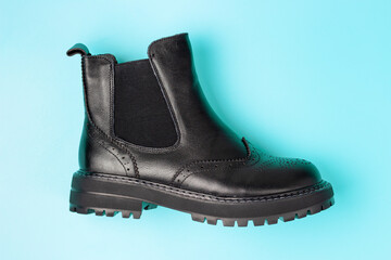 A black autumn boots on a pink background, view from above