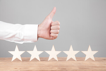 Male hand shows thumb up and five star rating.