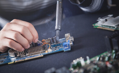 Computer hardware engineering. Engineer soldering computer motherboard