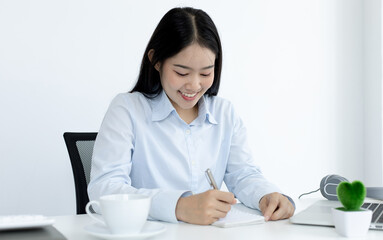 Young white Asian woman studying via the internet in her home office.